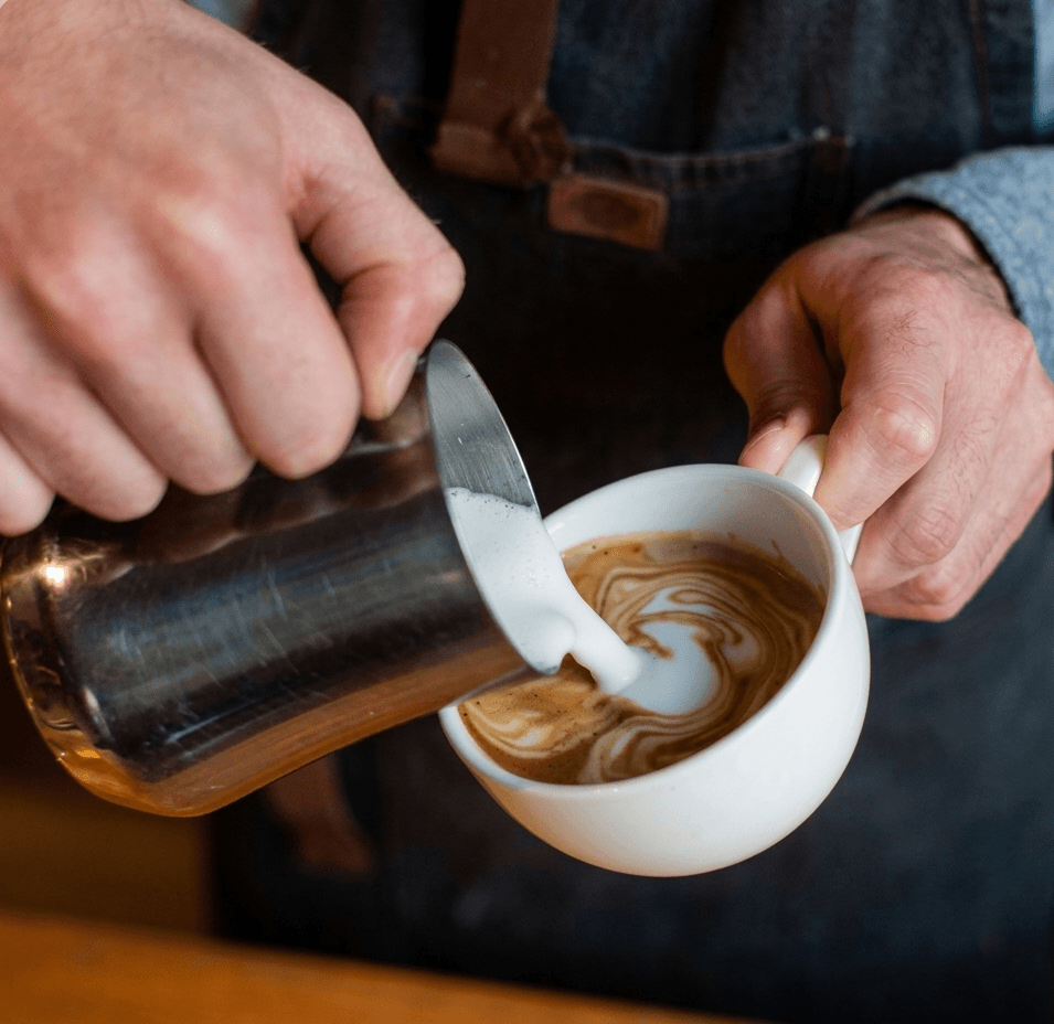 Barista vertiendo leche en taza
